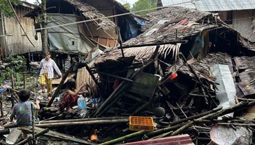 سكان يجلبون المياه بجوار منزل مدمر في هيناتوان بمقاطعة سوريغاو ديل سور في 3 كانون الاول 2023، بعد زلزال بقوة 7.6 درجات هز المنطقة في 2 منه (أ ف ب).