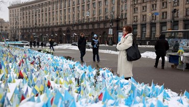 امرأة تنظر إلى أعلام تخلد ذكرى الجنود الأوكرانيين القتلى، في ميدان الاستقلال في كييف (1 ك1 2023، أ ف ب). 