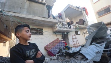 فتى ينظر بينما يتفقد فلسطينيون الأضرار الناجمة عن قصف إسرائيلي على خان يونس في جنوب قطاع غزة (8 ك1 2023، أ ف ب).