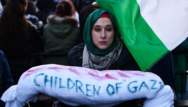 متظاهرة تحمل ما يُشبه الكفن كُتب عليه "أطفال غزة"، في مسيرة من أجل فلسطين في وسط لندن (9 ك1 2023 - أ ف ب).