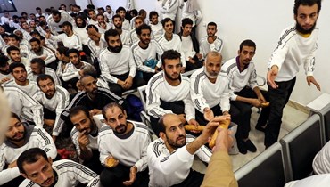 مهاجرون مصريون يتلقون الخبز خلال انتظار ترحيلهم في طرابلس (12 ك1 2023، أ ف ب). 