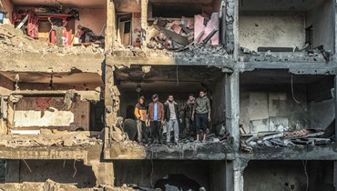 فلسطينيّون يتفقّدون مبنى نصف مدمّر في أعقاب القصف الإسرائيلي على رفح، في جنوب قطاع غزة (أ ف ب). 