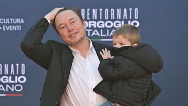 الملياردير إيلون ماسك يحمل طفله خلال تجمّع سياسي لليمين المتطرّف في روما (16 ك1 2023 - أ ف ب).