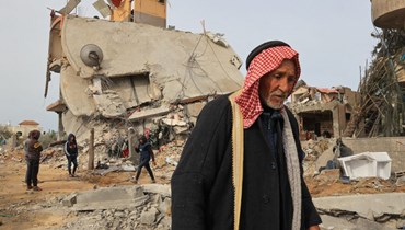 رجل مسنّ يقف أمام منزل مدمّر في خان يونس وسط تواصل القصف الإسرائيلي على القطاع (أ ف ب).