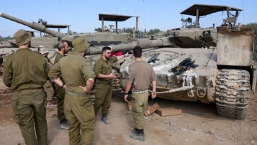 جنود إسرائيليّون يتجمّعون حول دبابات بالقرب من قطاع غزة (أ ف ب). 