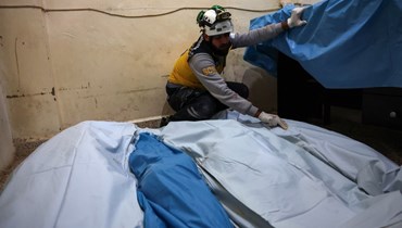 متطوع في الدفاع المدني السوري، المعروف باسم الخوذ البيضاء، يضع جثث الضحايا من نفس العائلة في المستشفى بعد غارات جوية روسية ليلاً بالقرب من بلدة أرمناز في الجزء الشمالي الغربي من محافظة إدلب السورية (26 كانون الأول 2023 - أ ف ب).