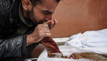 فلسطيني يُقبّل يد أحد أقربائه الذي قُتِل جرّاء القصف الإسرائيلي على غزّة (أف  ب).