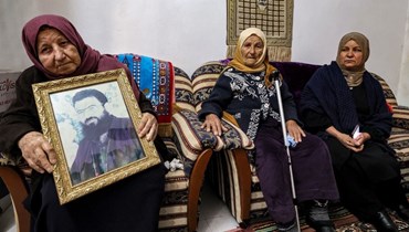 عائشة والدة صالح العاروري حملت صورة له في منزل العائلة في بلدة عارورة شمال رام الله في الضفة الغربية المحتلة (3 ك2 2024، أ ف ب).