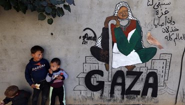 أطفال فلسطينيّون نازحون يقفون بجوار لوحة جدارية في رفح جنوب قطاع غزة (أ ف ب).