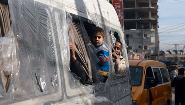 فلسطينيون ينظرون من نوافذ حافلة صغيرة في سوق في مخيم رفح للاجئين في قطاع غزة (أ ف ب).