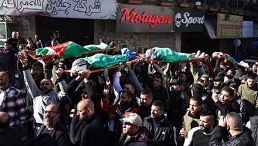 فلسطينيّون يحملون جثث ضحايا الغارات الإسرائيلية على جنين في الضفة الغربية (أ ف ب).