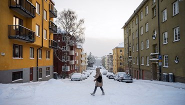امرأة تعبر الشارع بعد تساقط الثلوج في سوندبيبيرج، بالقرب من ستوكهولم (4 ك2 2024 - أ ف ب).