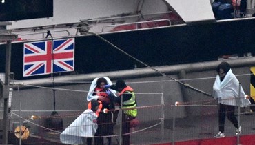 مهاجرون مع أطفال تم انقاذهم خلال محاولتهم عبور القناة الإنكليزية من فرنسا، ينزلون في مارينا في دوفر جنوب شرق إنكلترا (13 ك2 2024، أ ف ب).