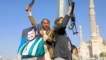 مقاتلون حوثيون يلوحون بأسلحتهم خلال احتجاج في العاصمة صنعاء بعد الضربات الأميركية والبريطانية (12 ك2 2024، أ ف ب).