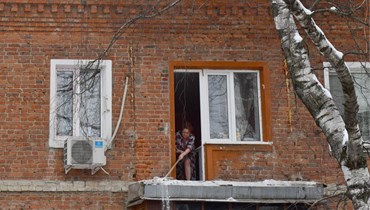 امرأة تنظف الثلج على شرفة مبنى متضرر بعد قصف أوكراني مزعوم على بيلغورود (10 ك2 2024، أ ف ب).