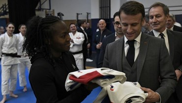 ماكرون يتلقى القميص الرسمي للفريق الفرنسي هدية خلال زيارته المعهد الوطني الفرنسي للرياضة والخبرة والأداء في باريس (23 ك2 2024، أ ف ب).