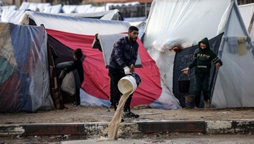 نازح فلسطيني يزيل المياه من خيمة غمرتها الأمطار، داخل مخيم موقّت في رفح، جنوب قطاع غزة (27 ك2 2024 - أ ف ب).