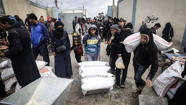 نازحون فلسطينيون يتلقون مساعدات غذائية في مركز للأونروا في رفح بجنوب قطاع غزة (28 ك2 2024، أ ف ب). 