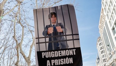 محتجون حملوا لافتة تصور بوتشيمون في السجن خلال تظاهرة ضد قانون العفو في ساحة بلازا دي إسبانيا في مدريد (28 ك2 2024، أ  ف ب). 