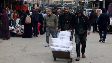 نازحون فلسطينيون ينقلون مساعدات غذائية تلقوها من الأونروا في رفح بجنوب قطاع غزة (28 ك2 2024، أ ف ب). 