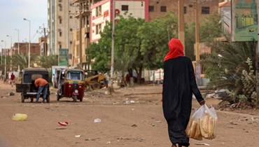 امرأة تحمل أكياس خبز خلال سيرها في أحد شوارع الخرطوم (18 نيسان 2023، أ ف ب).