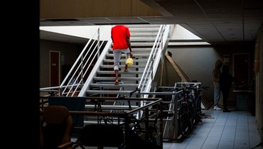 مهاجر يصعد الدرج في مبنى إداري تحول مقرا في فيتري سور سين على مشارف باريس (19 ك2 2024، أ ف ب).