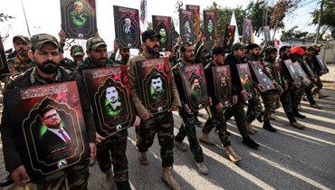 عناصر من قوات الحشد الشعبي العراقية يحملون صورا لقتلى الغارات الأميركية في غرب العراق، خلال تشييعهم في بغداد (4 ك2 2024، أ ف ب). 