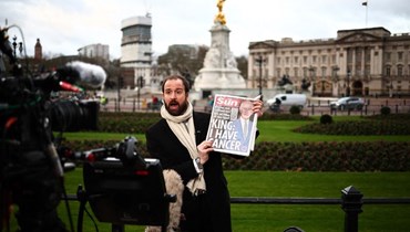 صحافي يعرض الصفحات الأولى للصحف حول سرطان الملك تشارلز الثالث خلال تقديم التقارير خارج قصر باكنغهام في لندن (6 ك2 2024، أ ف ب). 