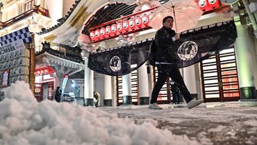 رجل يمر قرب مسرح كابوكيزا بينما تتساقط الثلوج في منطقة هيغاشي غينزا بوسط مدينة طوكيو (5 شباط 2024ـ أ ف ب).