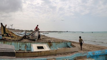 شبان يمنيون تجولوا بين قوارب على الشاطئ في منطقة الخوخة على الطرف الجنوبي لمدينة الحديدة على البحر الأحمر (12 شباط 2024، أ ف ب).