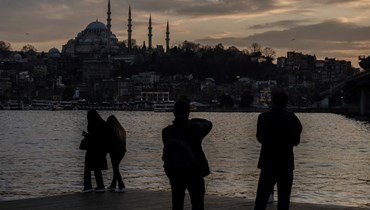 أشخاص يتأملون القرن الذهبي عند غروب الشمس في منطقة كاراكوي في إسطنبول، وبدا مسجد السليمانية في الخلفية (13 شباط 2024، أ ف ب).