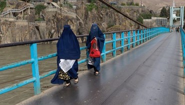 نساء أفغانيات يرتدين البرقع، يعبرن جسراً في منطقة فايز آباد في ولاية بدخشان (6 تموز 2023، أ ف ب).