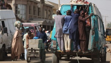 أشخاص يركبون حافلة صغيرة بالقرب من السوق في جيبيا (18 شباط 2024، أ ف ب). 