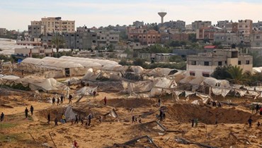 أشخاص يقفون حول الحفر الناجمة عن القصف الإسرائيلي في رفح بجنوب قطاع غزة (أ ف ب).