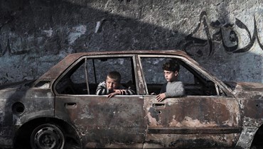 أطفال يجلسون في سيارة مدمرة في رفح، جنوب قطاع غزة، في (28 شباط 2024 - أ ف ب).