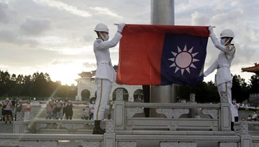 صورة ارشيفية- جنديان يطويان العلم الوطني خلال مراسم في ساحة الحرية بقاعة تشيانغ كاي شيك التذكارية في تايبيه (30 تموز 2022، أ ب).