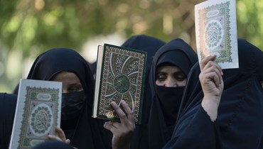 عراقيون يرفعون نسخا من القرآن الكريم خلال احتجاج في بغداد (22 تموز 2023، أ ب). 