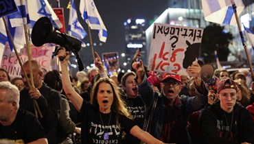  إسرائيليّون يلوّحون بالأعلام خلالتظاهرة مناهضة للحكومة في تل أبيب (أ ف ب). 