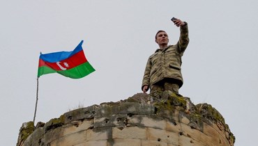 جندي أذربيجاني يلتقط صورة تذكارية من برج وسط كرباخ (أ ف ب).