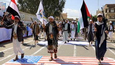  يمنيّون يدوسون على العلم الأميركي والإسرائيلي في العاصمة صنعاء، خلال مسيرة لدعم الفلسطينيين (أ ف ب). 