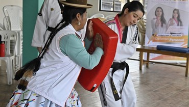 تجري مدربتا التايكوندو لورا روكا (الى اليمين) وامرأة من السكان الأصليين في أيمارا، ليديا مايتا، ورشة عمل للدفاع عن النفس والعلاج الشخصي تسمى قوة وارمي، لمنع العنف الجنسي في إل ألتو في بوليفيا (21 شباط 2024، أ ف ب). 