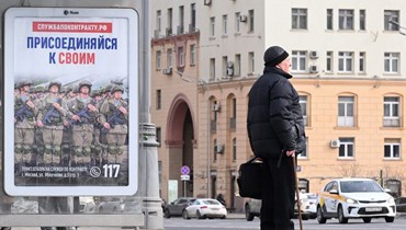رجل يقف بجوار لافتة إعلانية تروج للخدمة العسكرية التعاقدية، في موسكو (6 آذار 2024، أ ف ب). 