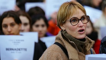 غودريش محاطة بمتظاهرين في باريس حملوا لافتات كتبت عليها أسماء ضحايا العنف في اليوم المرأة العالمي (8 آذار 2024، أ ف ب). 