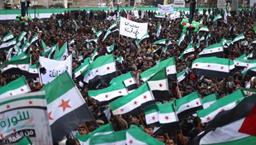 سوريون يشاركون في التجمع بإدلب شمال غرب سوريا (15 آذار 2024ـ أ ف ب). 