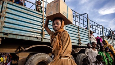 فتاة سودانية تحمل صندوقاً فيه بعض أغراضها بعد وصولها إلى مركز عبور اللاجئين في الرنك، شمال جنوب السودان (13 شباط 2024 - أ ف ب).