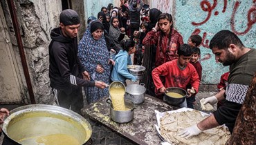 نازحون فلسطينيون يصطفون للحصول على الطعام الذي تبرعت به منظمة خيرية قبل وجبة الإفطار خلال شهر رمضان المبارك، في رفح بجنوب قطاع غزة في (16 آذار 2024 - أ ف ب).