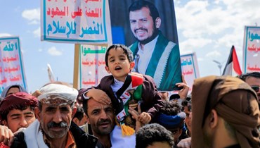 يمنيّون يرفعون لافتات وأعلام فلسطين خلال مسيرة في العاصمة صنعاء (أ ف ب). 