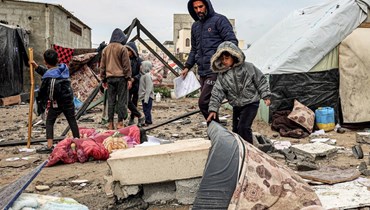 نازحون فلسطينيون يتفقّدون الأضرار التي لحقت بخيامهم بعد القصف الإسرائيلي خلال الليل على مخيم رفح للاجئين (أ ف ب). 