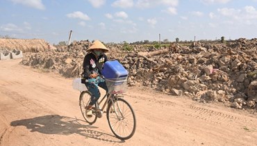 امرأة تنقل على دراجتها عبوات بلاستيكية للمياه العذبة، في مقاطعة بن تري بجنوب فيتنام (19 آذار 2024ـ أ ف ب). 