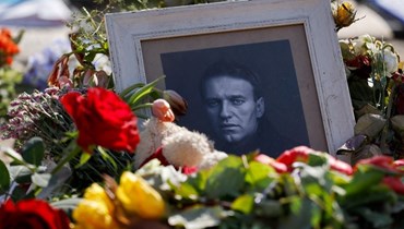 زهور وضعت بجوار صورة لنافالني عند نصب تذكاري موقت أقيم أمام السفارة الروسية في برلين (19 آذار 2024، أ ف ب). 